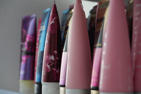 A close-up shot of various colorful cosmetic product tubes lined up on a shelf.