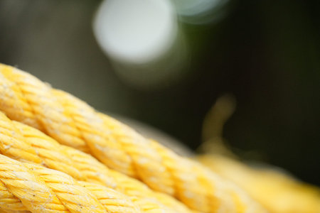 Thick yellow rope shows textured detail with bright bokeh lights in the dark background.の写真素材