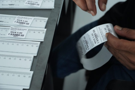A person is carefully handling tickets with barcodes and prices at Follow More Plaza, likely for an...