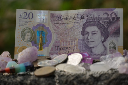 A twenty pound banknote stands tall amidst scattered coins, diverse crystals, and a unique rocket...