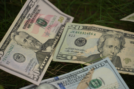 Close-up detail of American fifty, twenty, and one hundred dollar bills lying flat on the green...