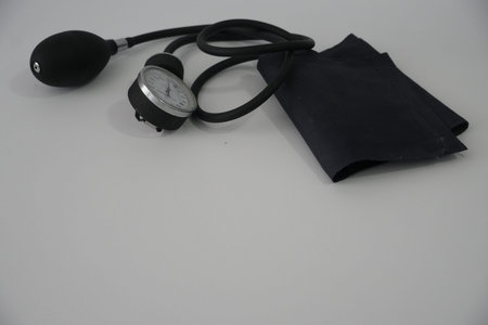 The black cuff and analog gauge of a blood pressure monitor are displayed on a white surface.