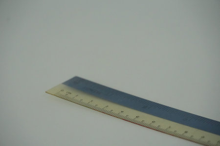 Two school rulers, one blue and one yellow, are casually placed on a bright white surface.