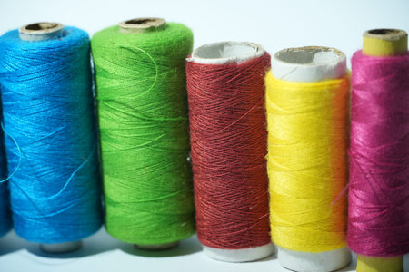 Five brightly colored spools of thread including blue, green, red, yellow, and pink are shown.