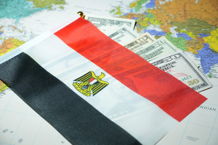 The Egyptian flag is placed on US dollar banknotes over a detailed world map.