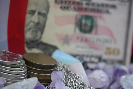 A fifty-dollar bill, coins, and scattered crystals are placed on a flag-patterned surface.