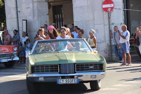 People vintage, Senigallia, Italy 12 August 2019 is an international music festival focused on American music and culture of the 1950s. In the photo: parade of vintage cars and people dressed in vintaのeditorial素材