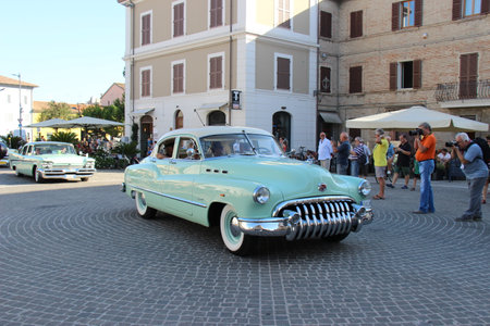 People vintage, Senigallia, Italy 12 August 2019 is an international music festival focused on American music and culture of the 1950s. In the photo: parade of vintage cars and people dressed in vintaのeditorial素材