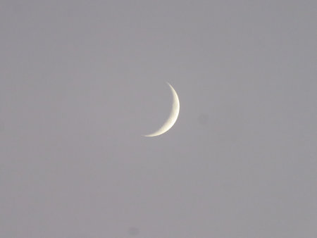 A closeup shot of a crescent moon under a cloudy skyの写真素材