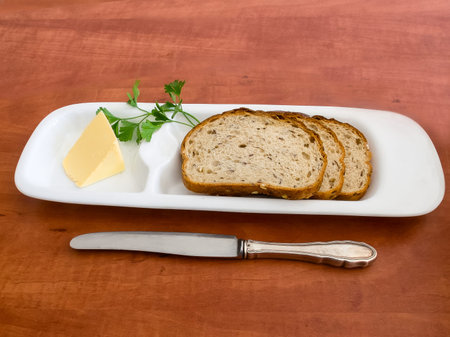 Slices of bread and butter on a plate with a butterdish and a knife   on a table