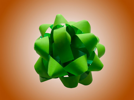 Green gift wrap bow isolated over a brown backgroundの写真素材