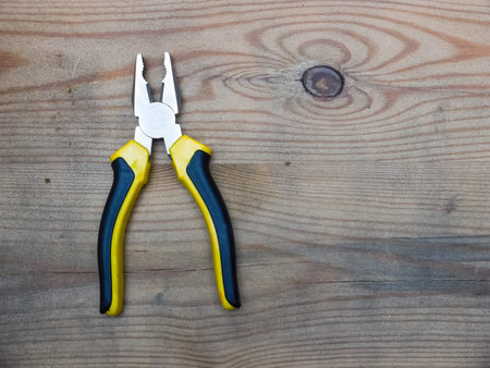 Combination cutting pliers on wooden background. Top view.