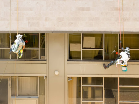 Two professional workers washing windows on a building