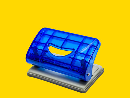Blue office hole puncher against yellow backgroundの写真素材