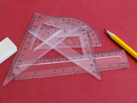 Protractor, rulers, pencil and eraser on red.の写真素材