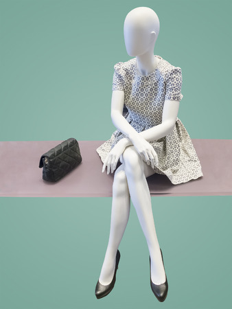 Sitting female mannequin, against green background. No brand names or copyright objects.の写真素材