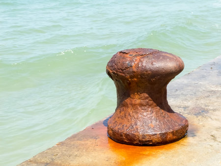 Old iron rusty mooring bollard at a harbor