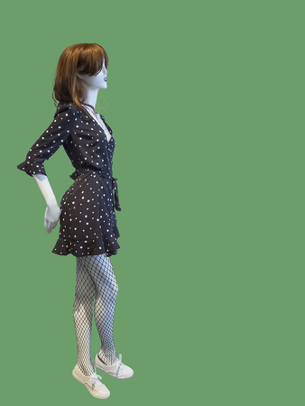 Full-length female mannequin wearing polka dot dress, isolated on green background. No brand names or copyright objects.の写真素材
