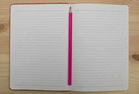 Notebook and red pencil on wooden board.の写真素材
