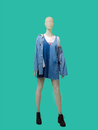 Full length female mannequin dressed in jeans jacket and sundress, isolated on green background. No brand names or copyright objects.の写真素材