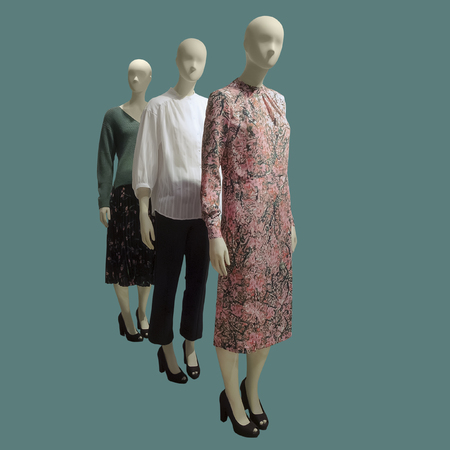 Three female mannequins dressed in fashionable clothes over green background. No brand names or copyright objects.の写真素材