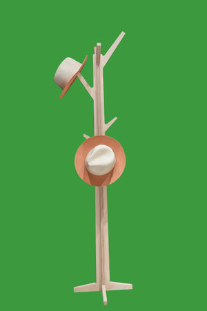 Two straw hats hanging on wooden hanger, isolated on green background.