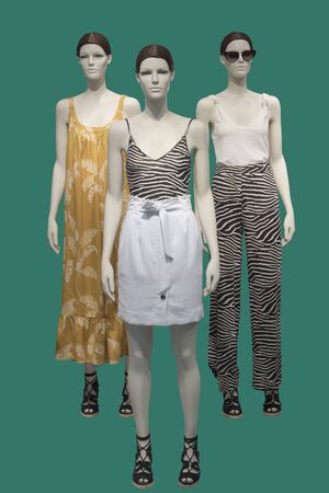 Three female mannequins dressed in fashionable clothes over green background. No brand names or copyright objects.の写真素材