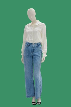 Full length female mannequin dressed in a white blouse and blue jeans, isolated on green background. No brand names or copyright objects.の写真素材