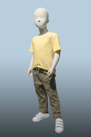Child mannequin dressed in yellow t-shirt and khaki trousers, isolated. No brand names or copyright objects.の写真素材