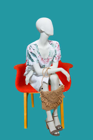 Sitting female mannequin wearing fashionable clothes, isolated on blue background. No brand names or copyright objects.の写真素材