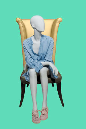 Sitting female mannequin wearing blue casual dress, isolated on green background. No brand names or copyright objects.の写真素材
