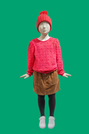 Full length image of a child display mannequin wearing warm fashionable clothes isolated on a green backgroundの写真素材