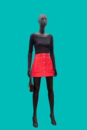 Full length image of a female display mannequin wearing black blouse and red skirt isolated on a blue backgroundの写真素材