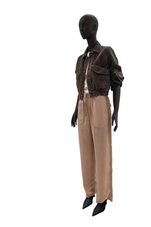 Full length image of a female display mannequin dressed in a black denim jacket and brown trousers isolated on white backgroundの写真素材