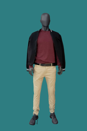 Full length image of a male display mannequin dressed in black sport jacket, burgundy sweater and white trousers isolated on blue backgroundの写真素材