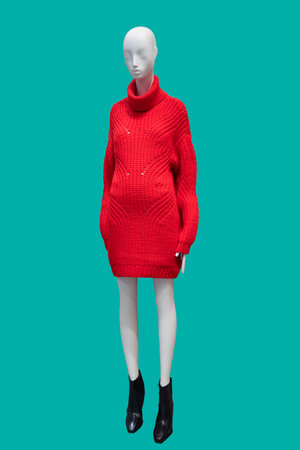 Full length image of a female display mannequin wearing fashionable red wool knitted dress isolated on green backgroundの写真素材