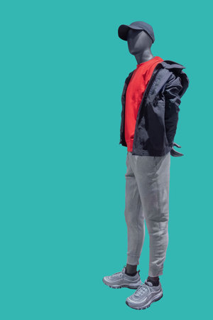 Full length image of a male display mannequin wearing black jacket, red shirt and gray pants isolated on blue backgroundの写真素材