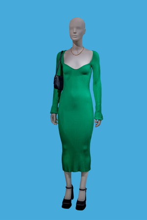 Full length image of a female display mannequin wearing fashionable green knitted dress isolated on blue backgroundの写真素材