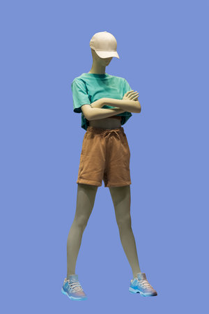 Full length image of a female display mannequin dressed in green top and brown shorts, isolated on blue backgroundの写真素材
