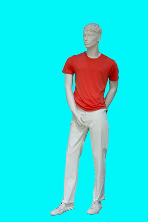Full length image of a male display mannequin wearing red t-shirt and white trousers isolated on green backgroundの写真素材