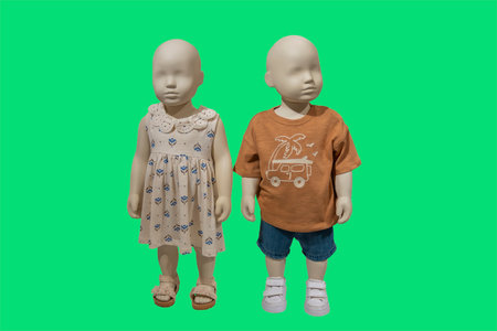 Full length image of two children displays mannequins wearing fashionable summer clothes isolated on green backgroundの写真素材