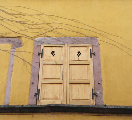 Wooden window on yellow wall in the town of Riga, Latviaの写真素材