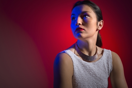 Portrait of a beautiful stylish woman in dramatic lighting sitting with her head turned to the side facing blank copyspaceの写真素材