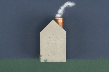 Conceptual house with billowing smoke emitting from the chimney depicting energy efficiency, alternative eco friendly fuel or air pollution and carbon dioxide emission, with copyspaceの写真素材