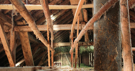 Old wooden barn from the inside, with sunlight only coming from a little roof window and some chinks...