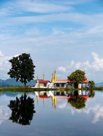 Pagoda with golden spiers on a mirroring lake Inle, Myanmar / Burma.の写真素材