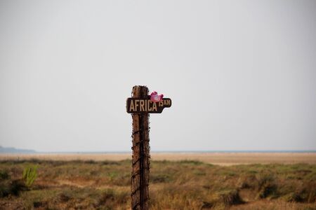 Signpost leading the way 15 km before Africa with a pink soft toy.の写真素材