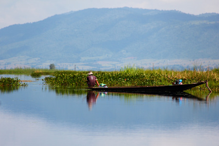Fisherman with a boat on the mirroring Lake Inle in Myanmar / Burma.のeditorial素材