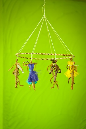 Voodoo mobile dolls hand-made from Bark  on green wallの写真素材