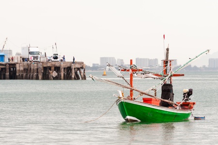 Green fishing boat thai on the sea in daylight time with jettyの写真素材